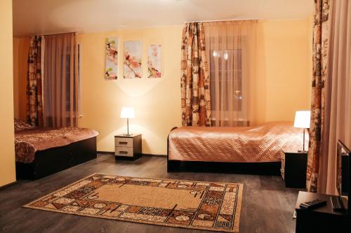 ヴォログダにあるMini-Hotel Aquarelのベッド2台とラグ付きのホテルルームです。