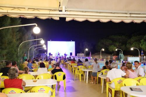 a large group of people sitting at tables at a screen at Village Camping Joker in Cavallino-Treporti