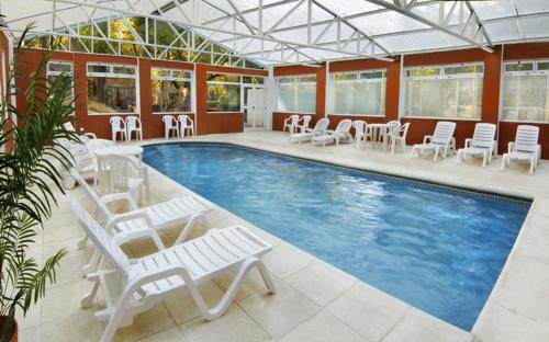 una gran piscina con sillas blancas, mesas y sillas en Graz Hauser Cabañas en Villa General Belgrano