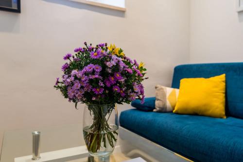 a vase of purple flowers on a table next to a couch at Apartments Tereza in Dubrovnik