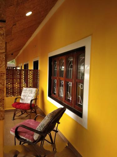 a room with two chairs and a window on a wall at Alegro Beach Homes in Palolem