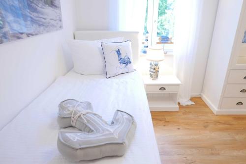 a white bedroom with a pair of shoes on a bed at Baabe Ferienwohnung Meerflair Ref_ in Baabe