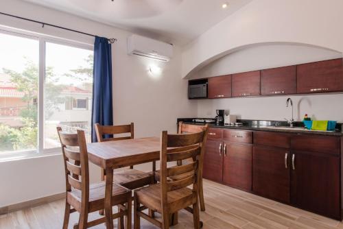 a kitchen with a wooden table and wooden chairs at Villas Picalu Studios & Suites in Puerto Aventuras