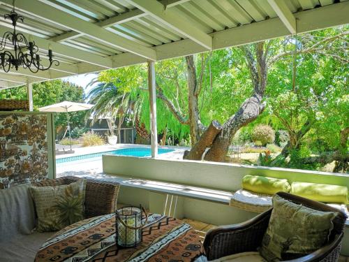 a patio with a table and chairs and a pool at Almond Cottage Bed & Breakfast in Somerset West