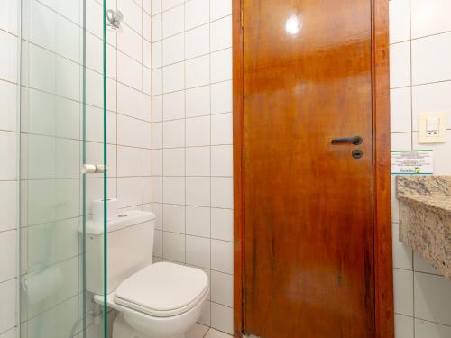 a bathroom with a toilet and a wooden door at Pousada Pé Na Areia in Caraguatatuba