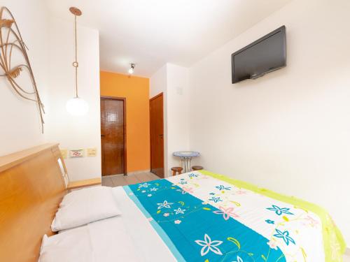 a bedroom with a bed and a tv on the wall at Pousada Pé Na Areia in Caraguatatuba
