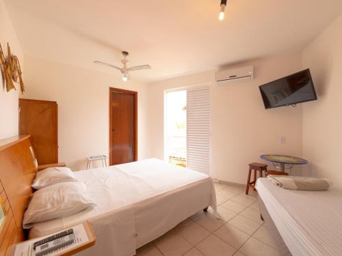 a bedroom with two beds and a tv on the wall at Pousada Pé Na Areia in Caraguatatuba