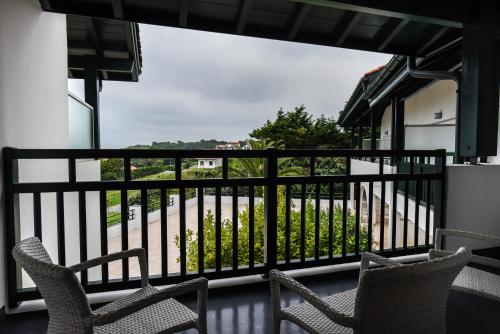 a balcony with chairs and a view of a yard at Hôtel La Réserve in Saint-Jean-de-Luz