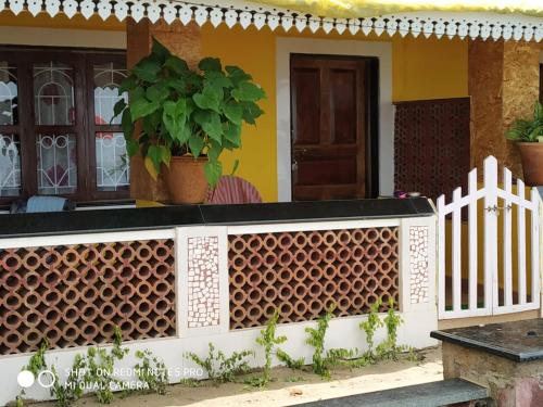 a house with a white fence and a plant at Alegro Beach Homes in Palolem