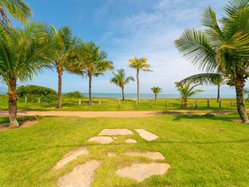a stone path in a field with palm trees at Pousada Pé Na Areia in Caraguatatuba