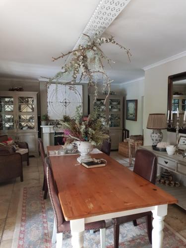 a dining room table with a vase of flowers on it at Almond Cottage Bed & Breakfast in Somerset West
