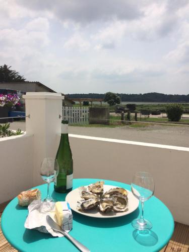 un tavolo con un piatto di ostriche e una bottiglia di vino di La Maison de pêcheur a Sarzeau
