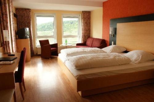 a bedroom with a large bed and a living room at Burg-Hotel in Obermoschel