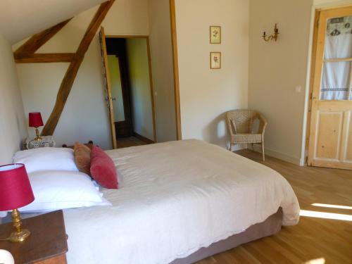 a bedroom with a large white bed with red pillows at Auberge de la Tuilerie in Andryes