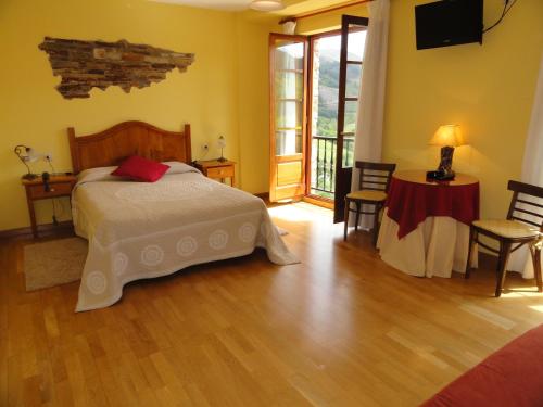 Un dormitorio con una cama y una mesa y sillas. en Hotel Restaurante Casa Petronila, en Taramundi