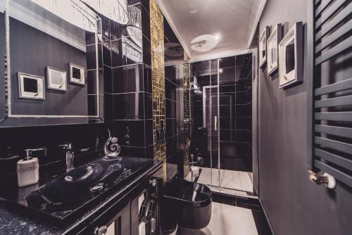 czarna łazienka z umywalką i prysznicem w obiekcie Glam Apartments w Toruniu