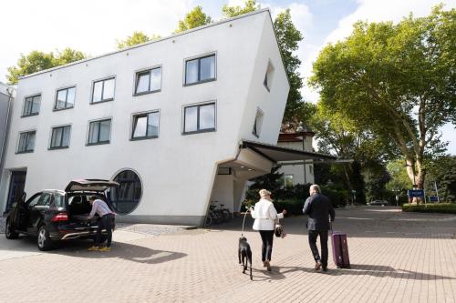 two people walking a dog in front of a building at Parkhotel Herne in Herne