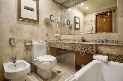 a bathroom with a toilet and a sink and a tub at Hotel Maria Luisa in Burgos
