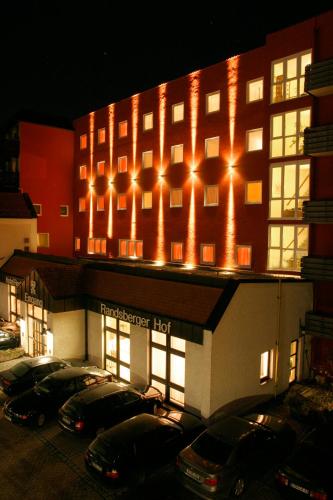 a lit up building with cars parked in a parking lot at Hotel Randsbergerhof in Cham