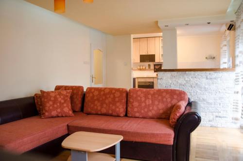 sala de estar con sofá marrón y cocina en Apartman White, en Belgrado