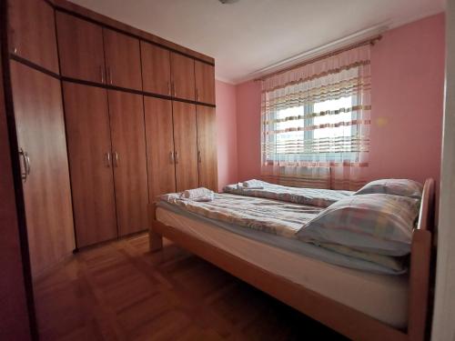 1 dormitorio con cama, armarios de madera y ventana en Apartman White, en Belgrado