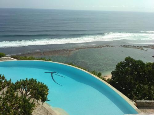 a swimming pool with the ocean in the background at Boutique hotel villa Cantik and karma beach club in Uluwatu