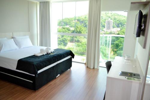 a bedroom with a bed and a large window at Evidence Hotel in Sapucaia