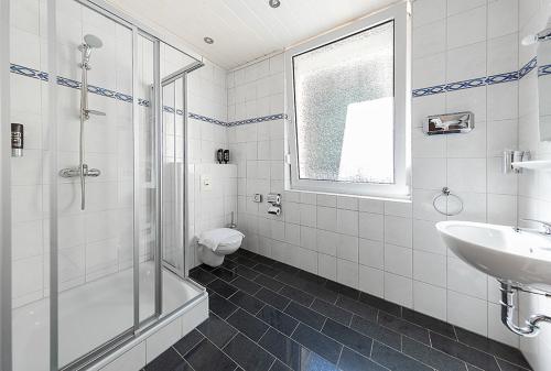 a bathroom with a shower and a sink and a toilet at Hotel Avalon in Landstuhl