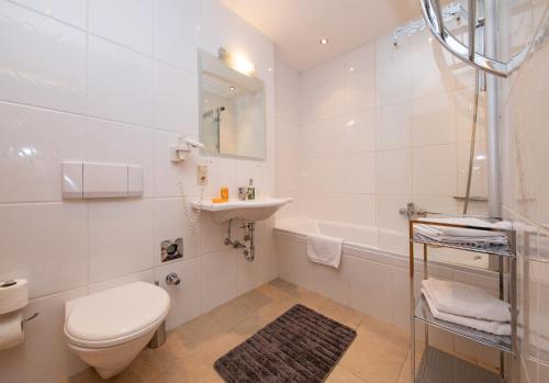 a bathroom with a toilet and a sink and a tub at Arabella Golf- und Ski-Appartement in Zell am See