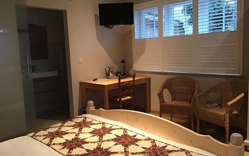 a bedroom with a bed and a desk and a television at B&B Wisteria in Herne