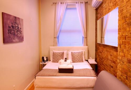 a bedroom with a bed with white sheets and a window at Chelsea Inn in New York