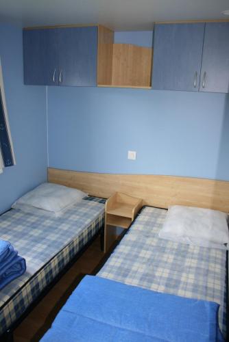 a room with two beds and a blue wall at Camping Le Walric in Saint-Valery-sur-Somme