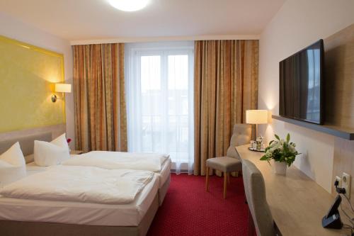 a hotel room with a bed and a desk and a television at Hotel 3 Linden in Leipzig
