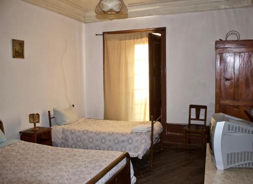 a room with two beds and a tv and a window at Residencial Rivoli in Fundão