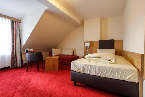 Habitación de hotel con cama y silla en Landhotel Goldener Stern, en Trautskirchen