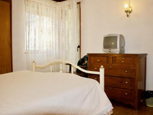 Residencial Tarouca في فانداو: غرفة نوم مع سرير وتلفزيون في خزانة