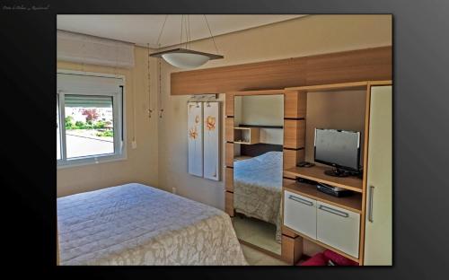 a small bedroom with a bed and a television at Cobertura Praia de Palmas in Governador Celso Ramos