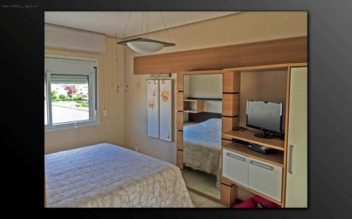 een kleine slaapkamer met een bed en een televisie bij Cobertura Praia de Palmas in Governador Celso Ramos