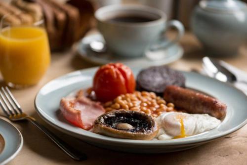 a plate of breakfast food on a table with a cup of coffee at Cottage Lodge Hotel in Brockenhurst