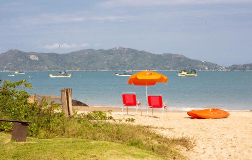 two chairs and an umbrella on a beach at Pousada dos Ingleses in Bombinhas