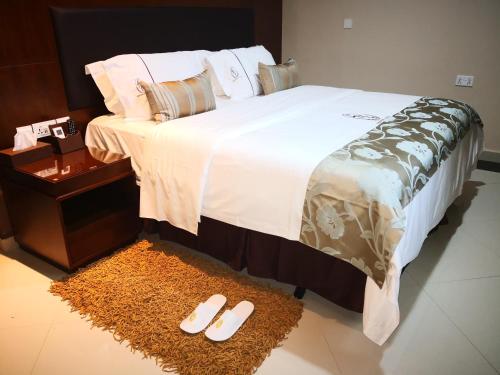 a bedroom with a large bed with slippers on the floor at Frederick's Lodge in Kumasi