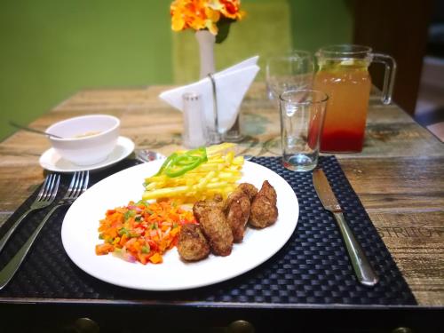 a plate of food with meat and vegetables on a table at Frederick's Lodge in Kumasi