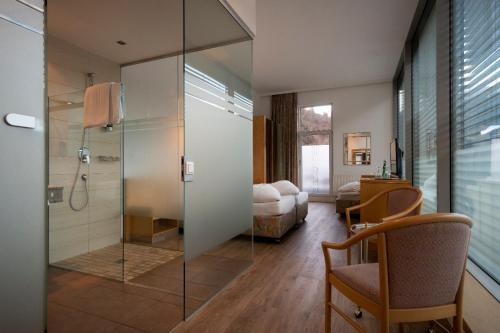 a bathroom with a glass shower and a bedroom at Hotel Bruggner Stub`n in Landeck