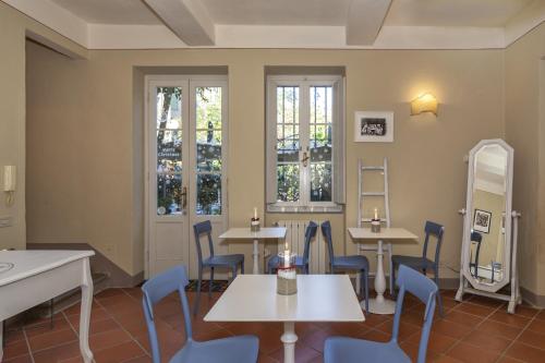 a dining room with tables and chairs and windows at Corte Meraviglia - Relais in Lucca