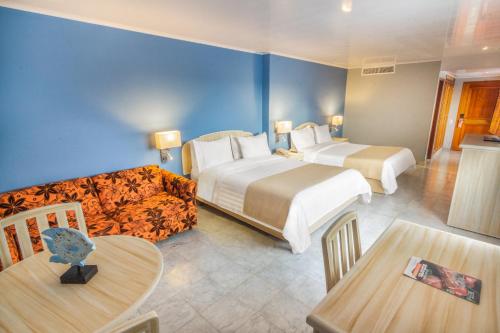 een hotelkamer met 2 bedden en een bank bij GHL Hotel Sunrise in San Andrés