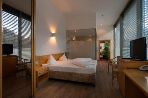 a hotel room with a bed and a tv and windows at Hotel Bruggner Stub`n in Landeck