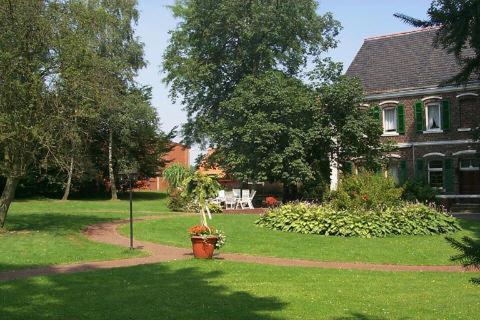 ein Haus mit einem Hof mit einer Topfpflanze im Gras in der Unterkunft Landhotel Meier Gresshoff in Oelde