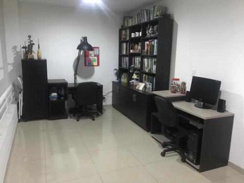 a room with two computer desks and a book shelf at Casa del Prado in Cali