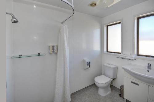 een witte badkamer met een toilet en een wastafel bij ASURE Adrian Motel in Dunedin