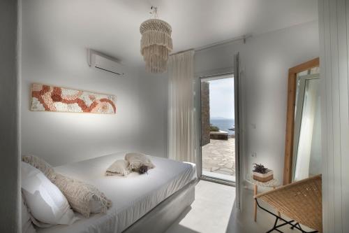 a white bedroom with a bed and a window at Simousi Villas in Kithnos